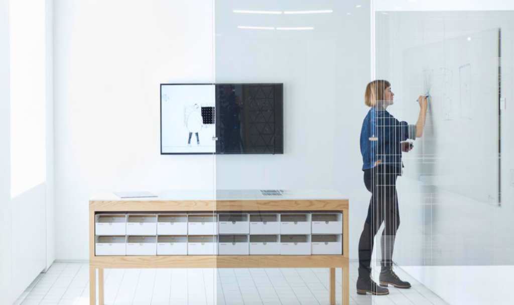 View of a woman in an office writing on a marker board.