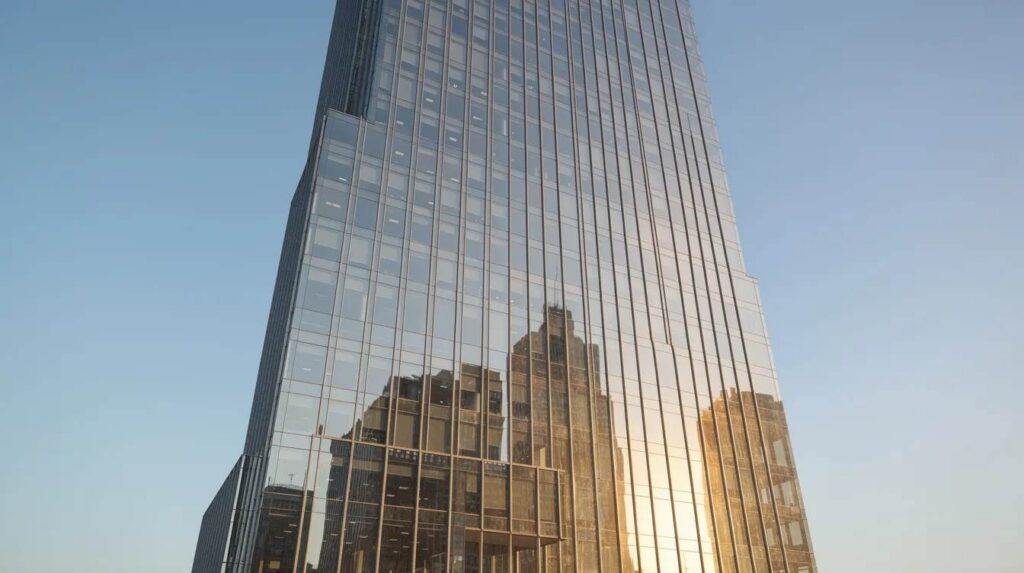 A tall glass office building features a uniform tinted facade that reflects sunlight, creating a sleek appearance against a clear blue sky. This commercial building utilizes window film to enhance energy efficiency, reduce glare, and protect against harmful UV rays while maintaining natural light for its occupants.